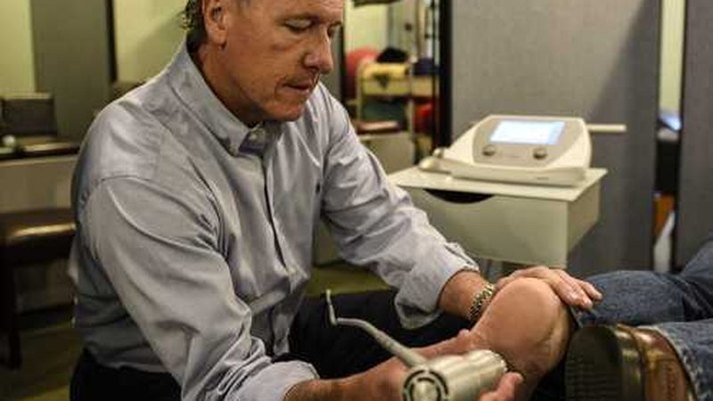Dr. Daniel Murray applying radial pulse therapy to a patient's knee