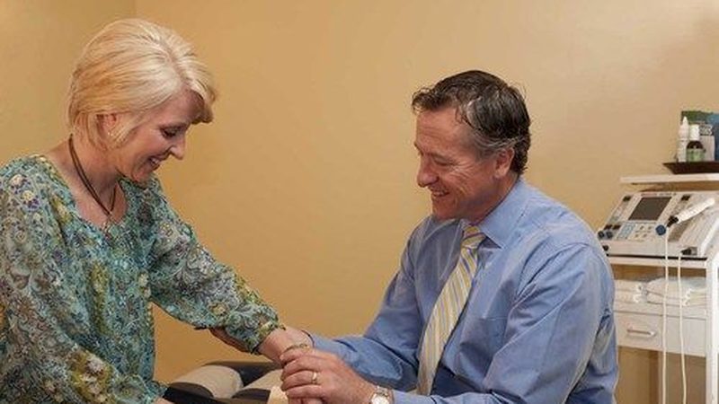 Dr. Daniel Murray examining a patient's arm in an exam room at Lake Country Health Center